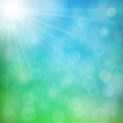 Abstract defocused nature background with blue and green blurred bokeh circles. Summer sun with light rays.