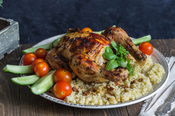 Baked chicken with a side dish of bulgur and fresh cucumbers, tomatoes