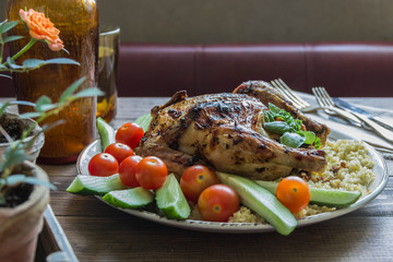 Baked chicken with a side dish of bulgur and fresh cucumbers, tomatoes