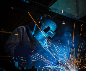 worker with protective mask welding metal