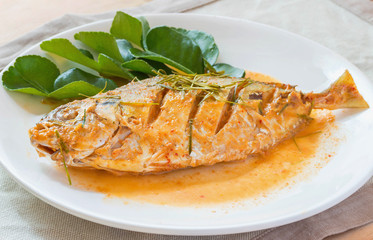 Fried fish in spicy curry sauce on white dish