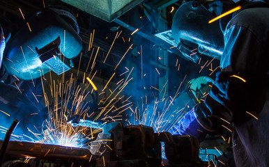 Teamworker with protective mask welding metal