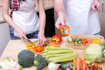 woman slicing vegetables and man offer pepper