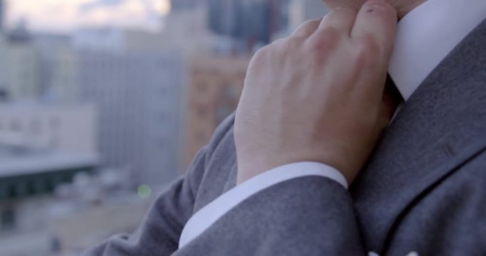 Extreme close up on Asian American business man as he loosens his tie then takes a drink of beer from a tall glass at sunset in Downtown Los Angeles, California.  Recorded in slow motion at 60fps.