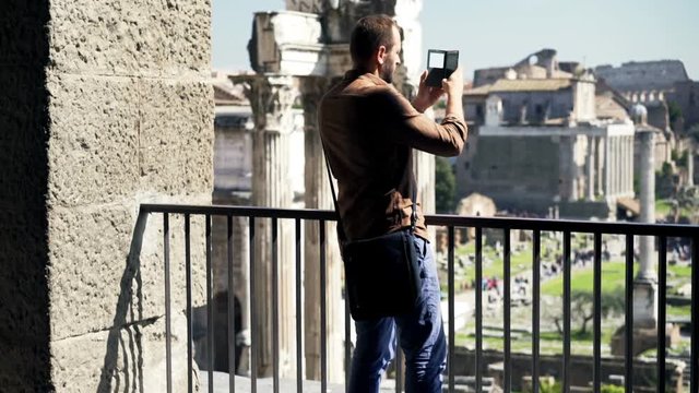 Happy man taking photo of the Roman Forum with cellphone in Rome, Italy
