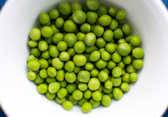 Органический зеленый горошек в белой тарелке.