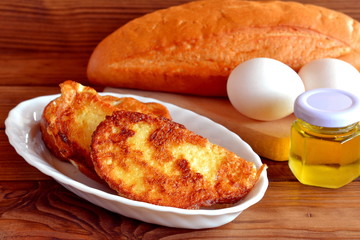 Roasted delicious crispy croutons on a plate. Fried bread with egg recipe. Easy meal idea. Simple quick breakfast recipe. One way to cook fried bread. Bun, eggs, olive oil, cutting board. Wooden table