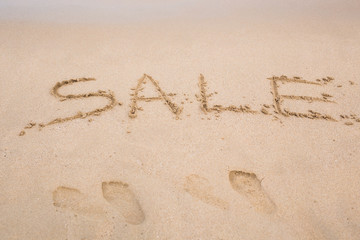 Summer sale handwritten in sand on a beach
