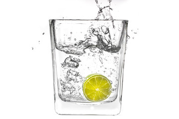 Lime slice falling in a glass of water
