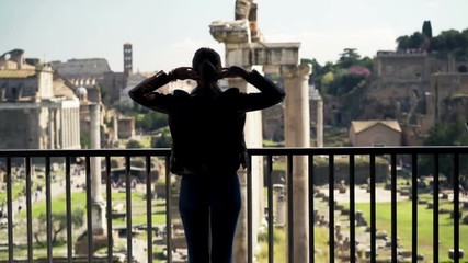 Woman stretching arms and admire view of the Roman Forum from balcony in Rome
