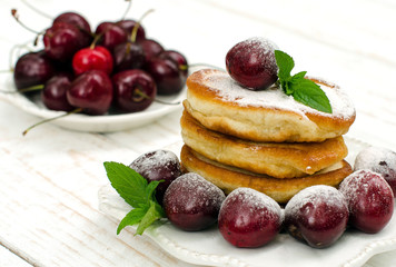 Pancakes with cherries, mint and powdered sugar