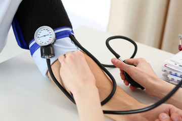 Female doctor hands measuring blood pressure to male patient