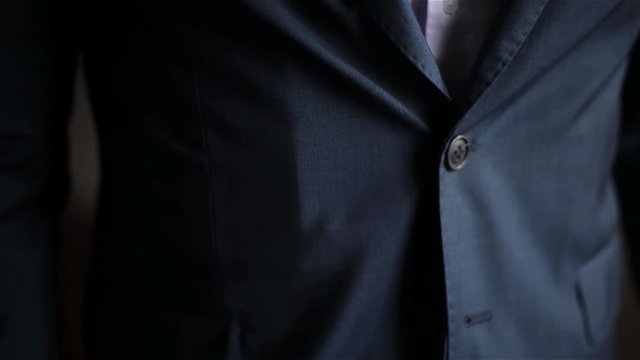 Young man dressed in the celebration, Groom buttons his jacket, wedding morning