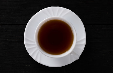 Tasse Tee auf schwarzem Hintergrund aus Holz - Ansicht von oben.