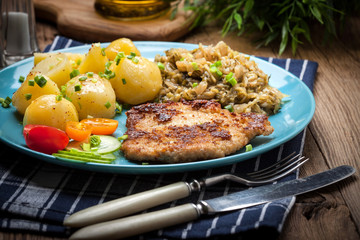 Fried pork chop, baked potatoes and fried young cabbage.