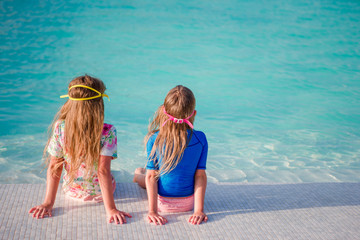 Fototapeta na wymiar Adorable little girls in swimming pool on summer vacation