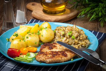 Fried pork chop, baked potatoes and fried young cabbage.