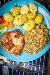 Fried pork chop, baked potatoes and fried young cabbage.