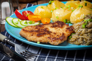 Fried pork chop, baked potatoes and fried young cabbage.