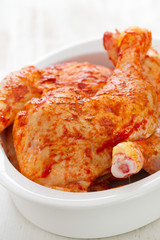 chicken in sauce in white dish on white woooden background