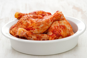 marinated chicken in white dish on white woooden background