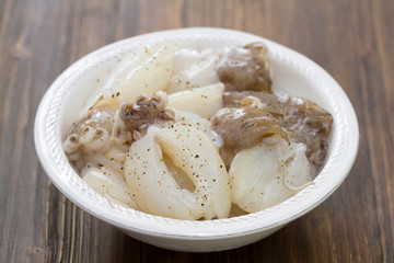 squids in white plate on brown wooden background