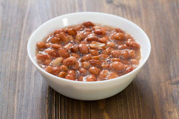 boiled beans in white dish on brown wooden background