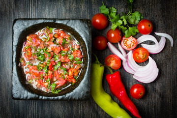Tomato sauce salsa and ingredients dark stone background.