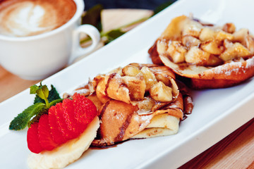 pancakes with fruit and coffee on wooden background. Beautiful restaurant serving the dessert