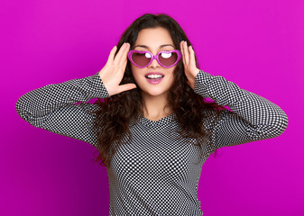 young woman beautiful portrait, posing on purple background, long curly hair, sunglasses in heart...