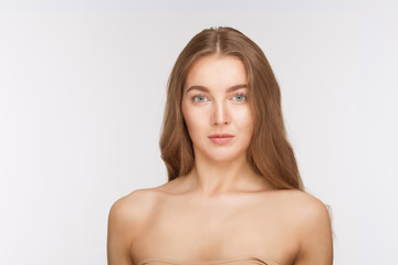 Fototapeta premium Portrait of serious beautiful shirtless lady over white background. Pretty woman looking directly at camera without any emotions.