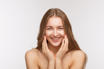 Obraz premium Closeup portrait of happy smiling beautiful shirtless lady posing for photographer over white background. Pretty woman touching her face skin with both hands.