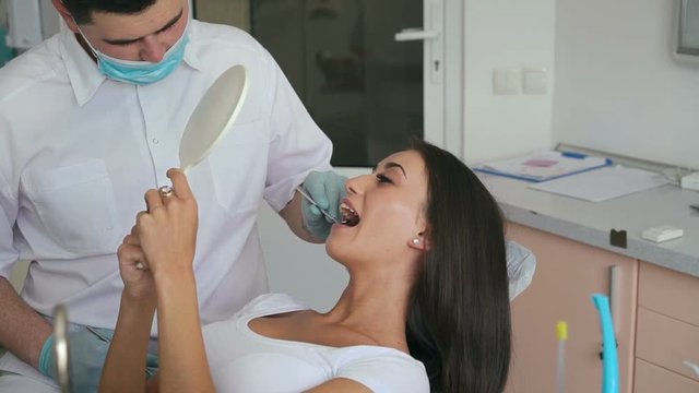 Woman having a check up at dentist's surgery with mirror