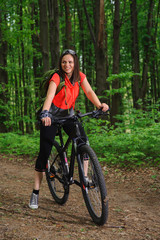 Naklejka premium Girl riding a bike in the woods