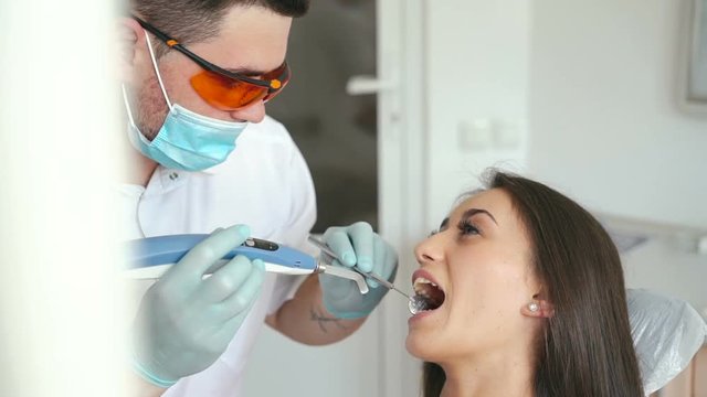 dentist using dental UV light equipment for polymer hardening