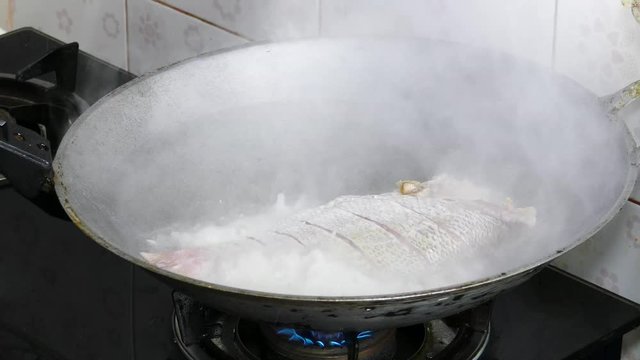 Frying Snapper fish in pan with vegetable oil.