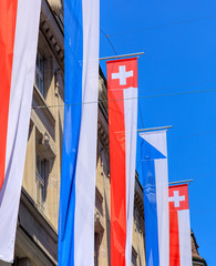 Facade of a building decorated with flags of Zurich and Switzerl
