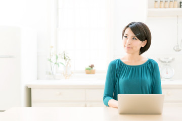 young asian woman using laptop in the kitchen