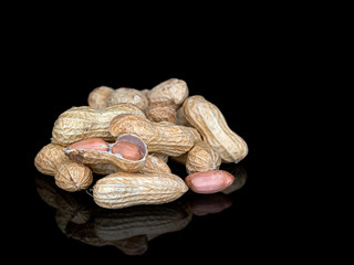 Monkey nuts, groundnuts, peanuts in shells on shiny black background.