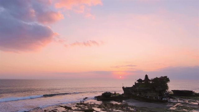 sea temple tanah lot sits on a rock formation at the sunset sun purple sky wide shot