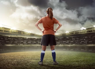 Afwasbaar Fotobehang Voetbal Vrouwelijke voetballer die op het veld staat