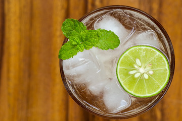 Top view of fresh cocktail with lime slice and mint on wood back