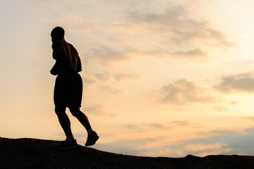 Silhouette of african american athlete jogging on sunset in mountains. Training outdoor. Sport and fitness concept