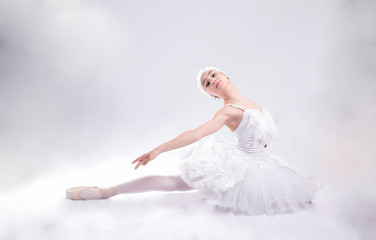 Naklejka premium Young ballerina in white is dancing on a white background