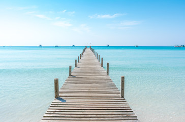Fototapeta premium Drewniany most na plaży nad morzem w błękitne letnie niebo. Molo