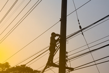 Silhouette, Electrician working at height on poles.