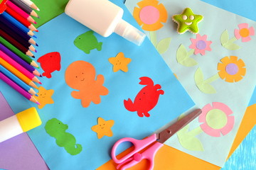 Paper octopus, fish, starfish, crab, flowers. Project idea using a colored paper. Applique work for children. Crafts from colored paper. Glue, scissors, pencils, eraser. Funny background