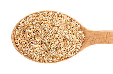 Wooden spoon with wheat groats isolated on white background.