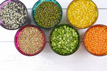 Multicolored clear glasses with various legumes ( green peas, re