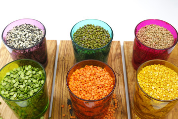 Multicolored clear glasses with various legumes ( green peas, re
